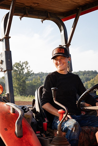 A person sitting on a tractor with a hat on.