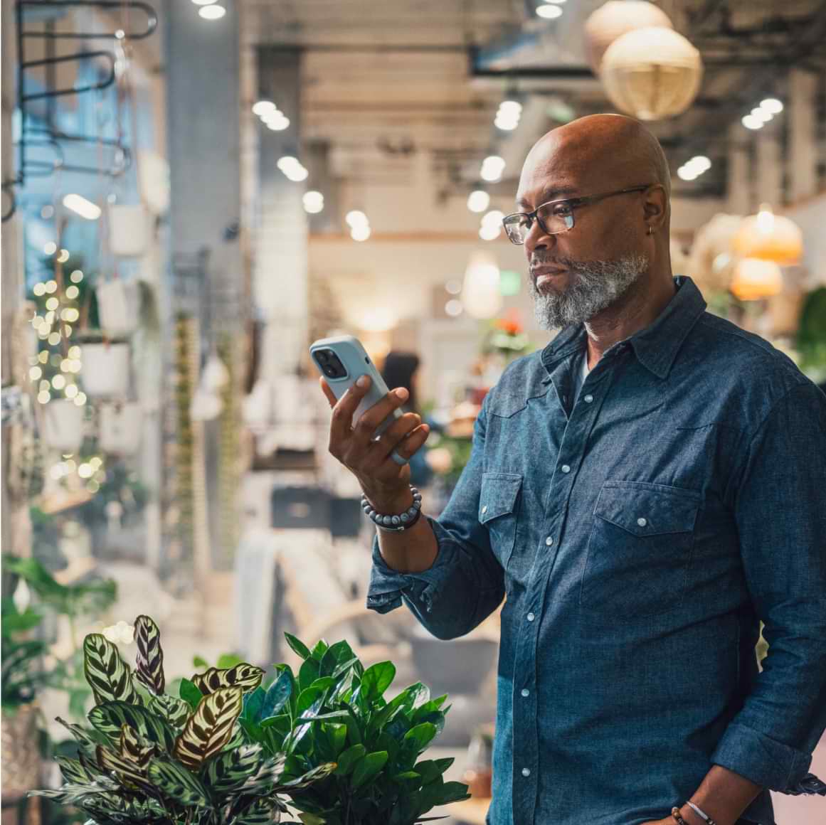 The owner of a plant shop looks at his business’s cash flow on his mobile device.