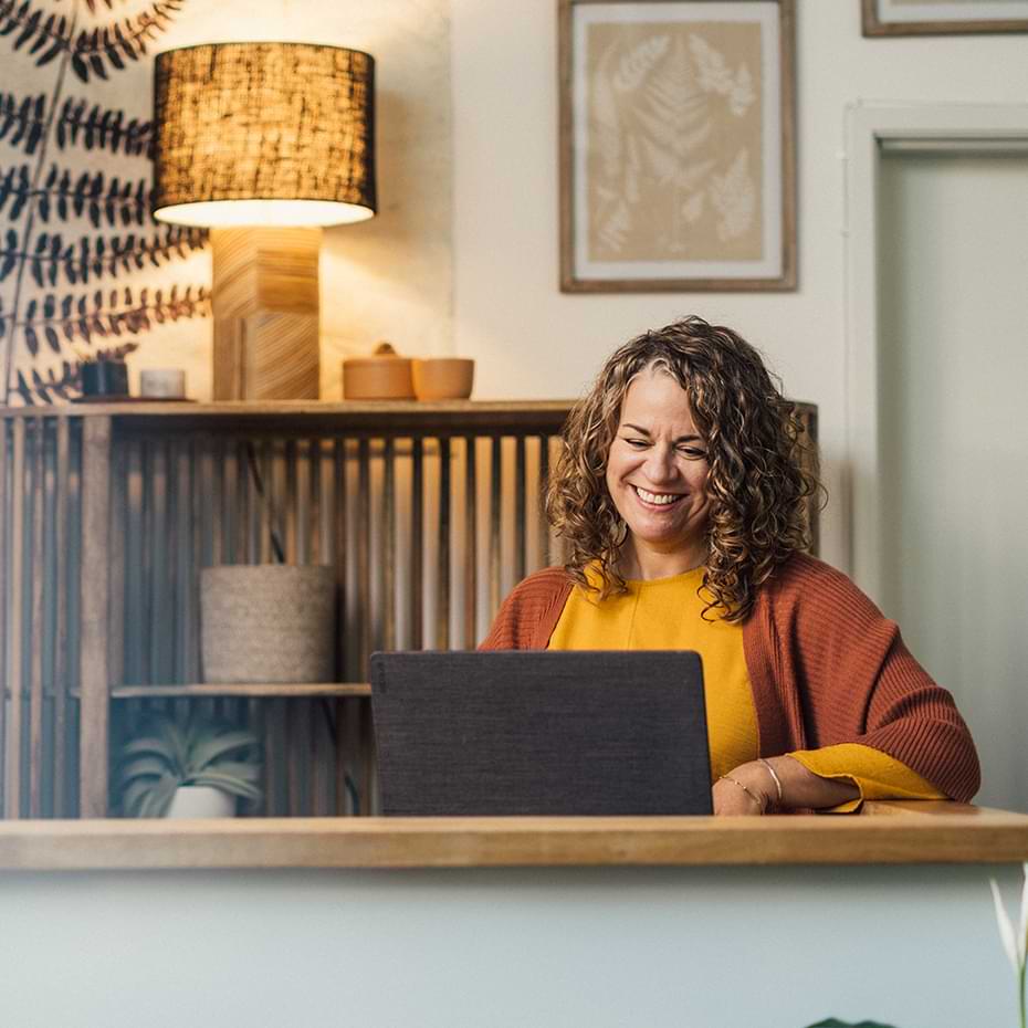 Business owner smiling at laptop.