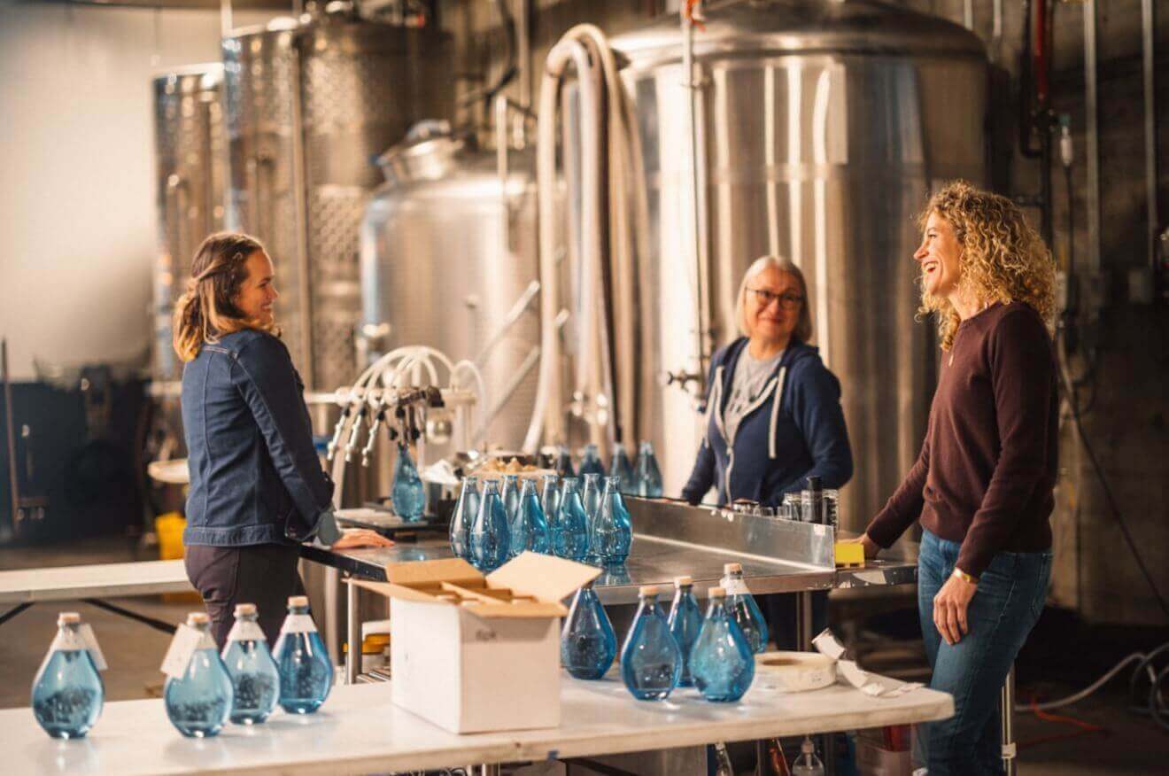 Small business owner talks with two employees in an artisanal gin distillery